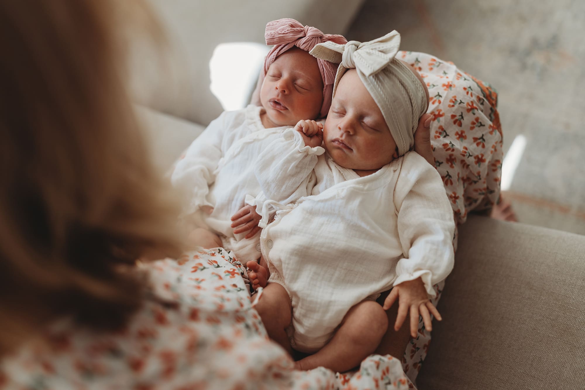 Atlanta newborn photographer capturing sleepy twin baby girls resting in their mother’s lap during an intimate in-home lifestyle newborn session