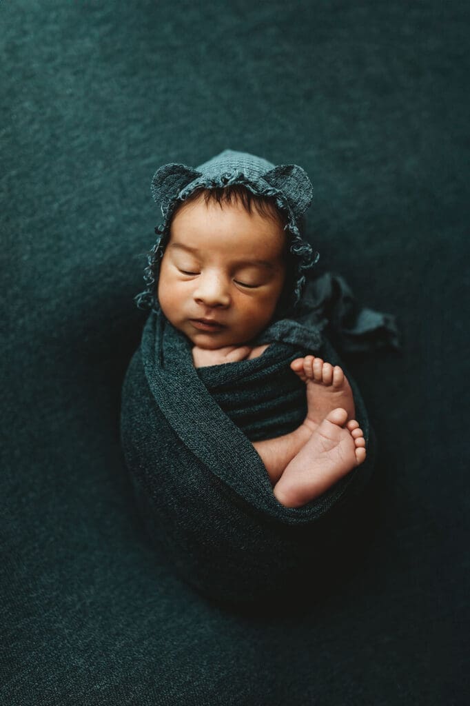 Marietta newborn photographer studio portrait of sleeping baby in teal wrap with bear bonnet