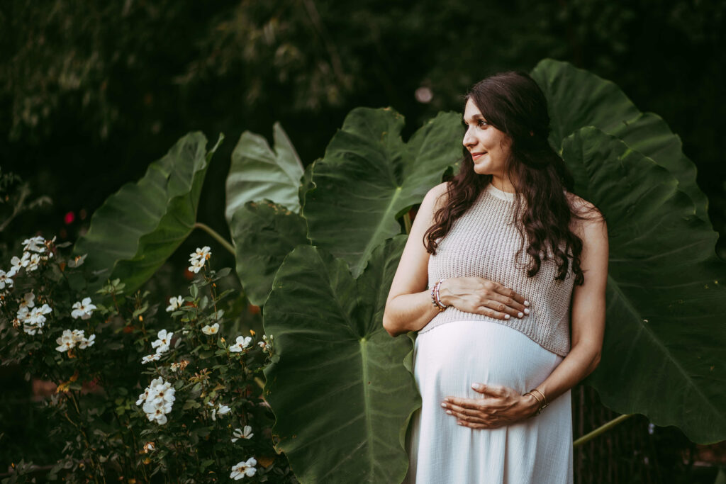 Pregnant mother in Midtown Atlanta green garden cradling her belly during maternity session