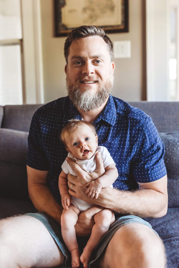 Atlanta newborn photography of dad holding baby, both looking at the camera during lifestyle session