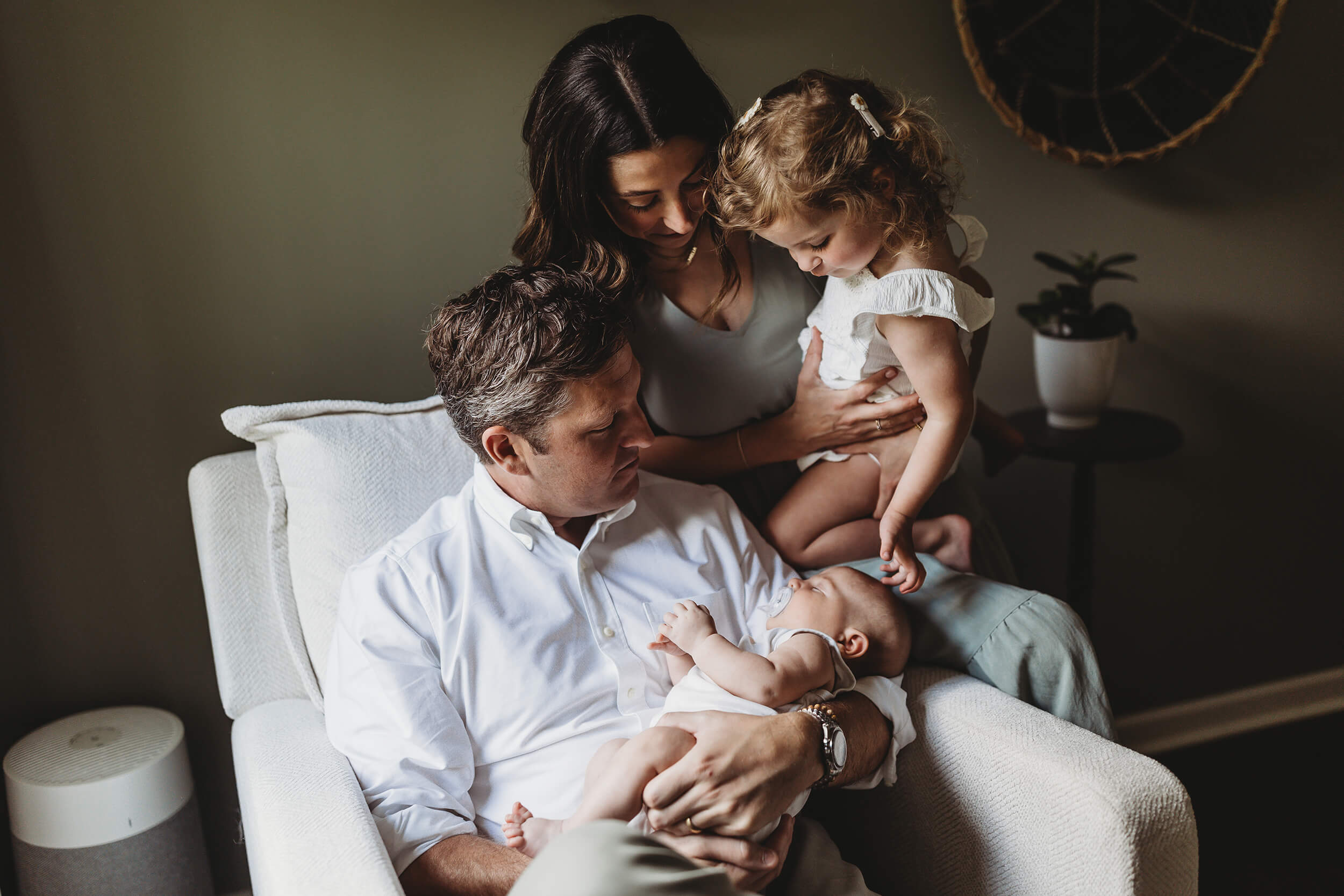 Parents with toddler and newborn sitting together during a relaxed in-home Atlanta newborn photography session capturing natural family connection