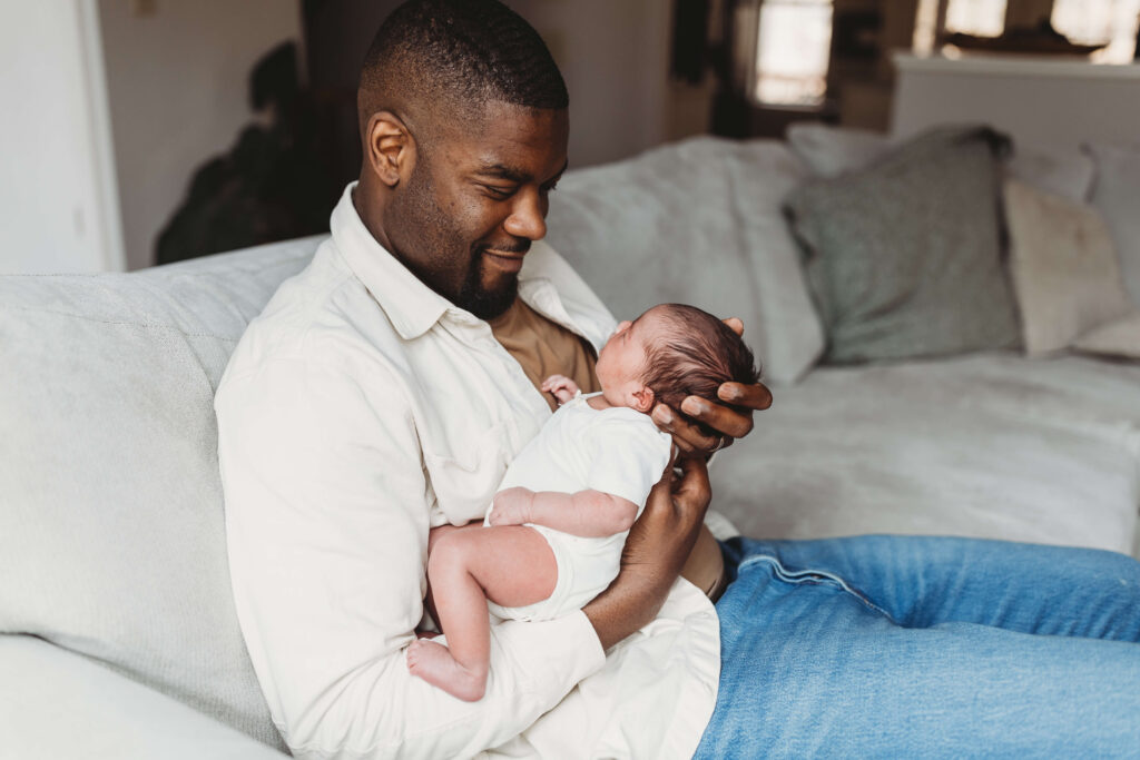 Dad holding newborn baby girl in natural light during Atlanta in-home newborn photography session