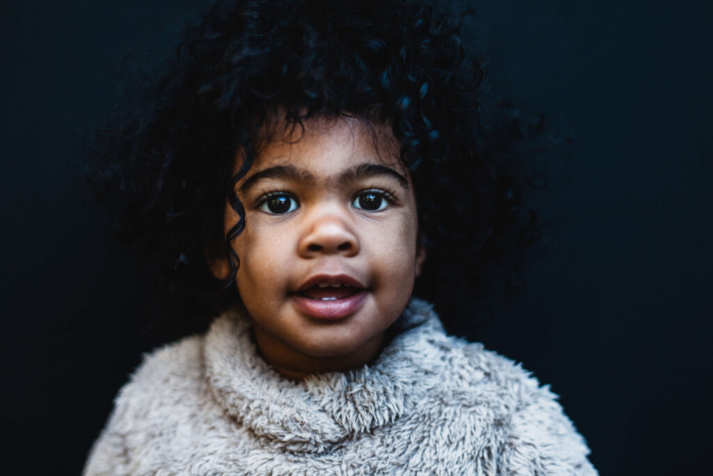 African American girl with dark curly hair smiling in a fuzzy sweater, natural Atlanta child portrait