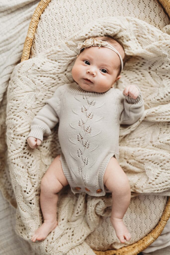 Atlanta newborn photographer capturing baby in moses basket wearing neutral knit outfit during in-home session