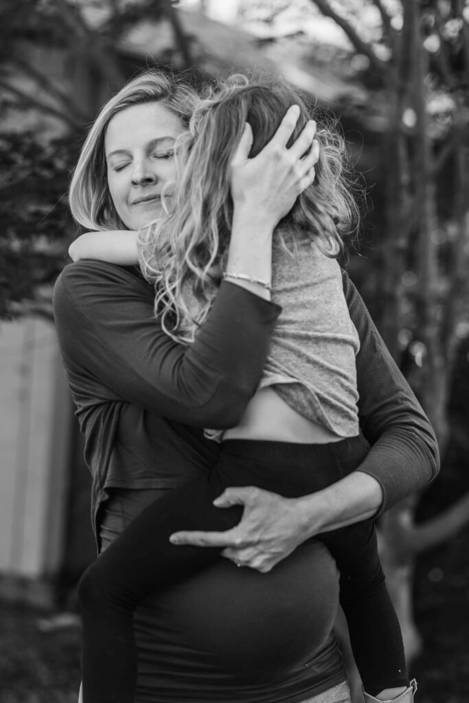Black and white maternity photo of pregnant mom holding toddler resting on her belly