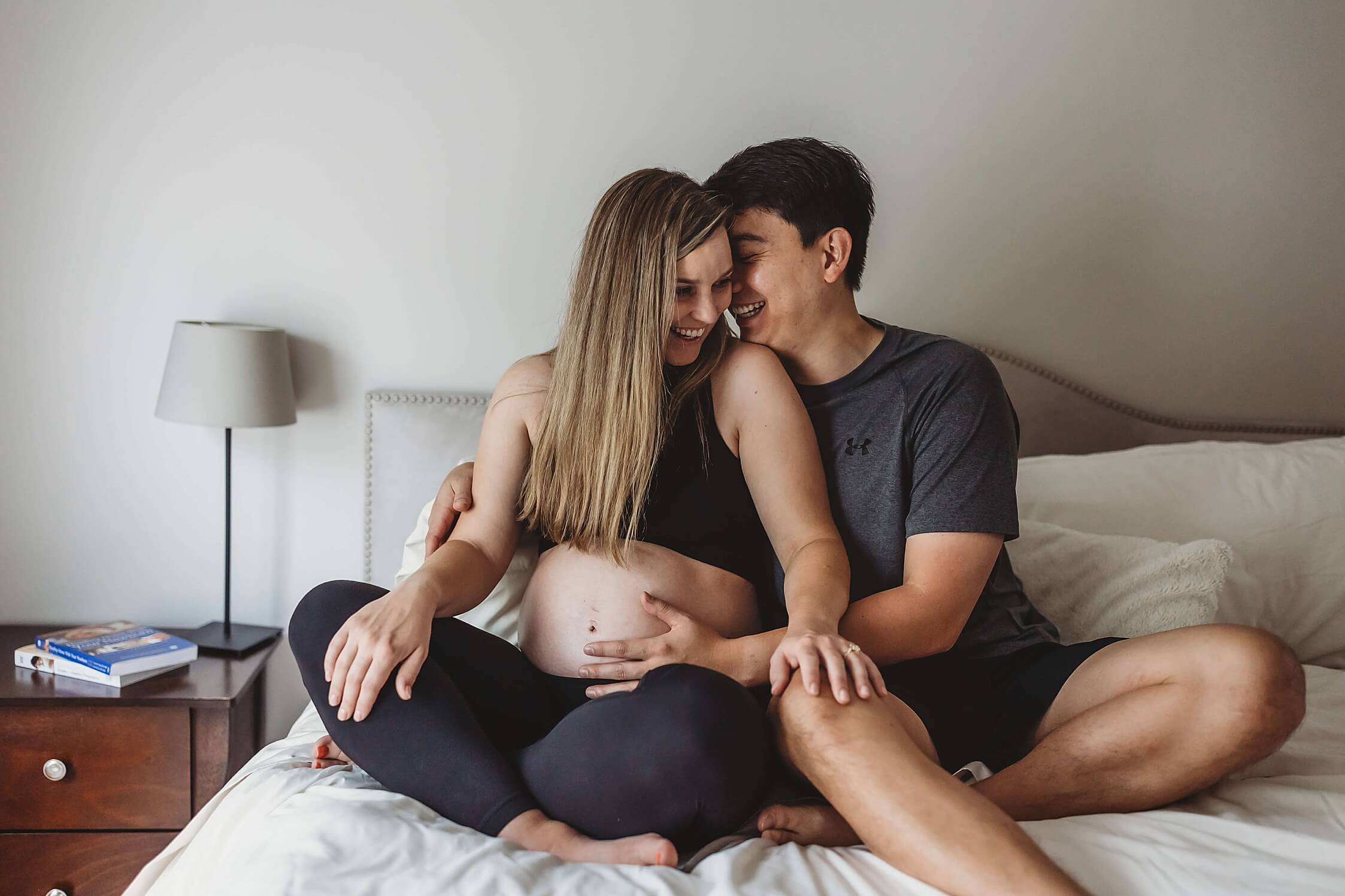 Atlanta maternity photographer capturing candid in-home moment of couple on bed during pregnancy