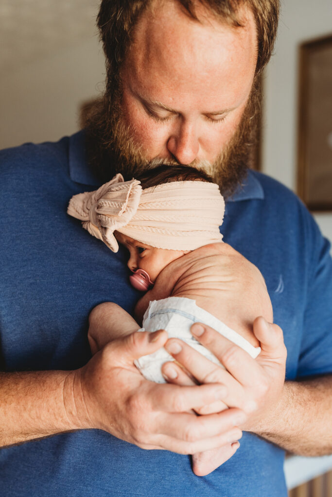 Dad holding his tiny newborn baby girl on his chest during a natural in-home newborn photography session in Atlanta.