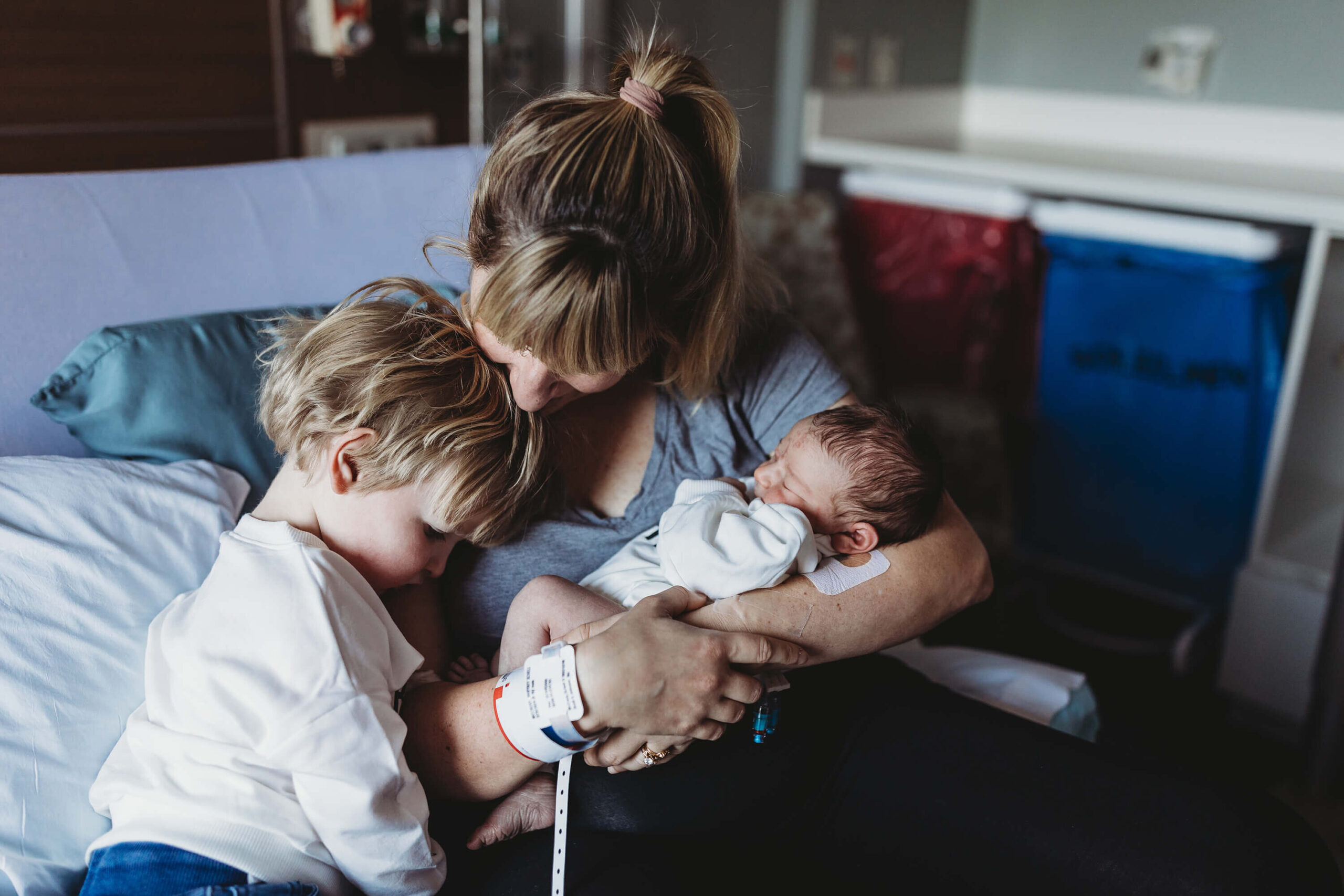 Mother holding newborn baby while comforting emotional older sibling during Fresh 48 session in Atlanta