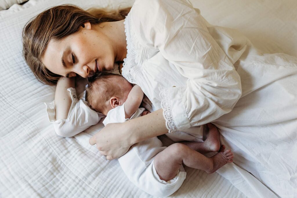 Sleepy newborn snuggles with mom on the bed during a cozy in-home newborn session in Buckhead, Atlanta
