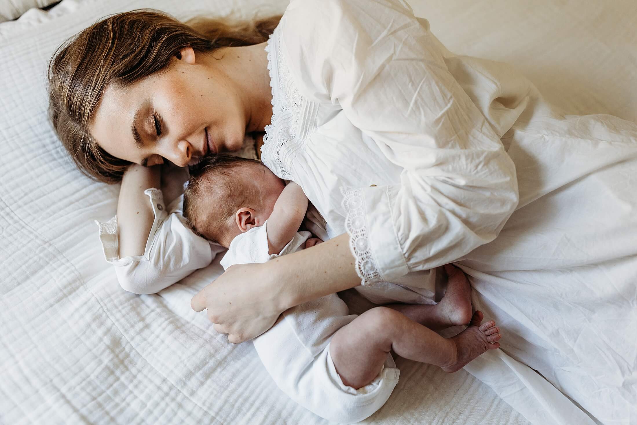 Sleepy newborn snuggles with mom on the bed during a cozy in-home newborn session in Buckhead, Atlanta