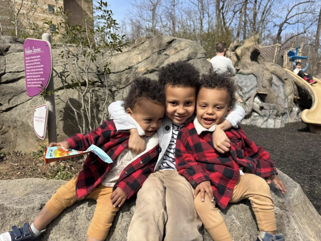 Three young children playing at the outdoor playground at Fernbank in Atlanta