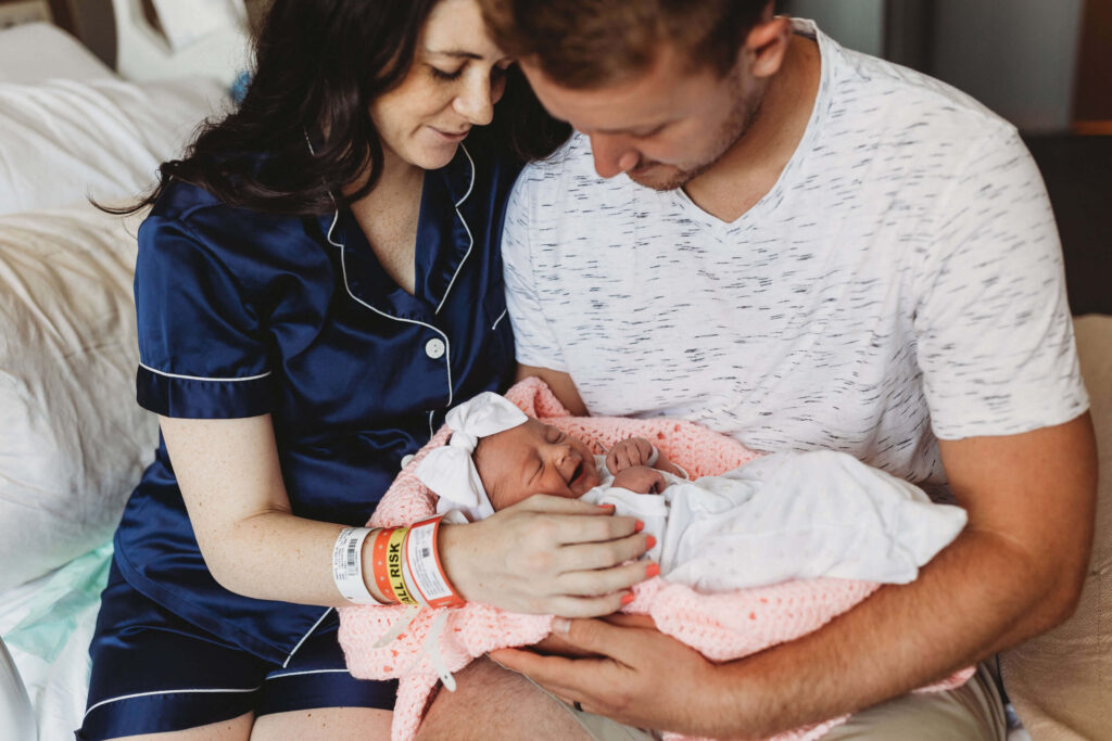 New parents at the labor and delivery unit of Piedmont Hospital holding their newborn baby close, sharing a joyful and emotional Fresh 48 moment in their hospital room.