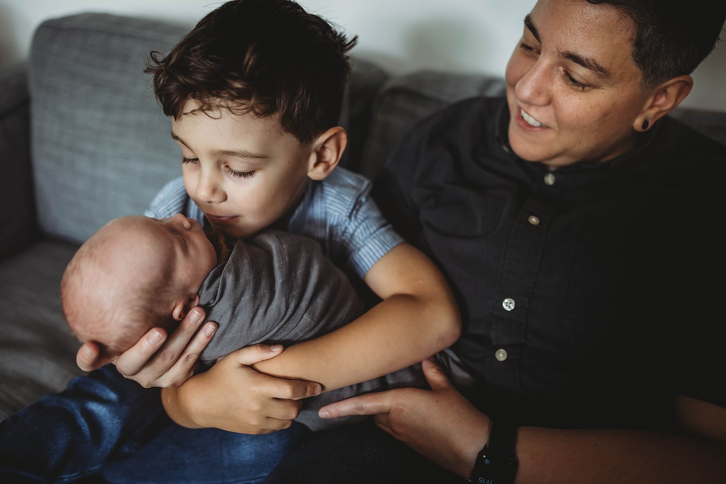 Big brother giving a kiss to newborn twins during in-home newborn session in Sandy Springs
