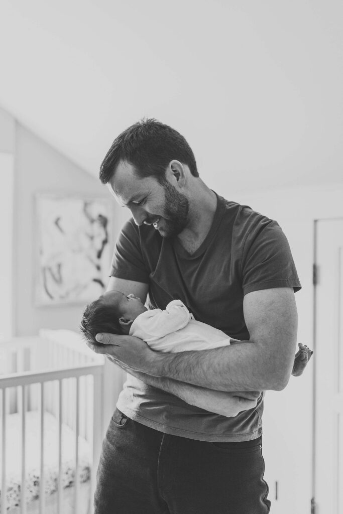Black and white portrait of a father holding his newborn baby during an Atlanta in-home newborn photography session.