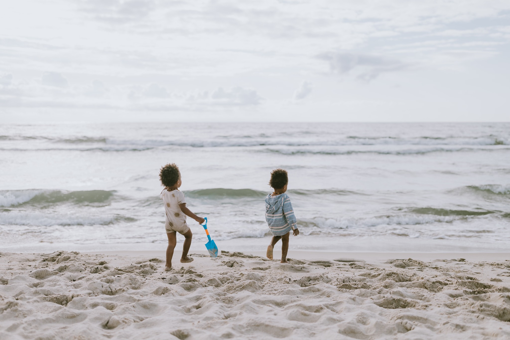 Twin toddlers exploring the beach shoreline together