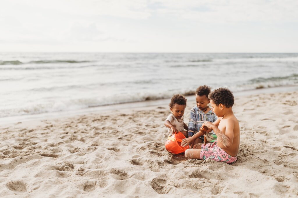 Three siblings playing near the shoreline during a family beach day