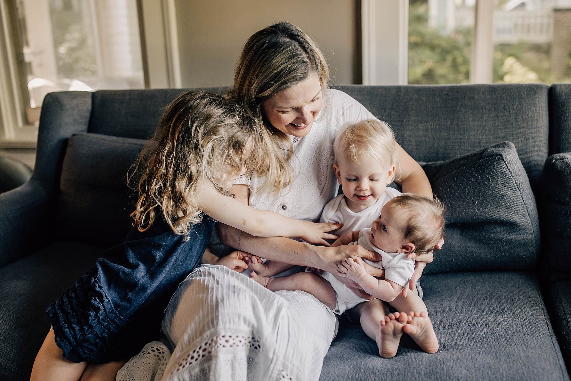 Mother holding her newborn with two older daughters at home in Atlanta during the newborn stage