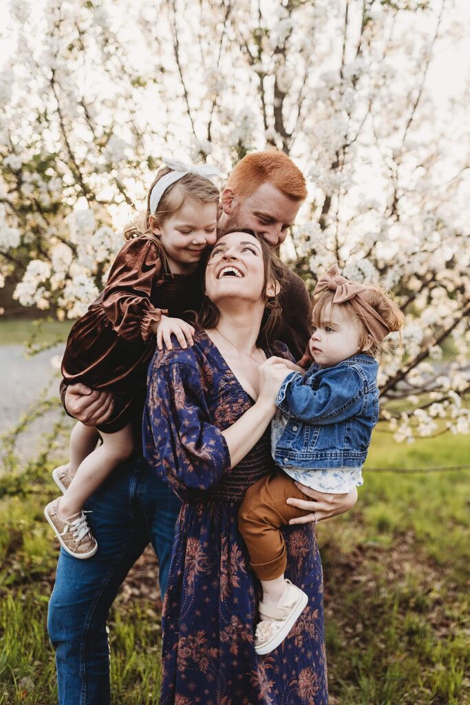 Family with two daughters laughing during session at Garrard landing park.