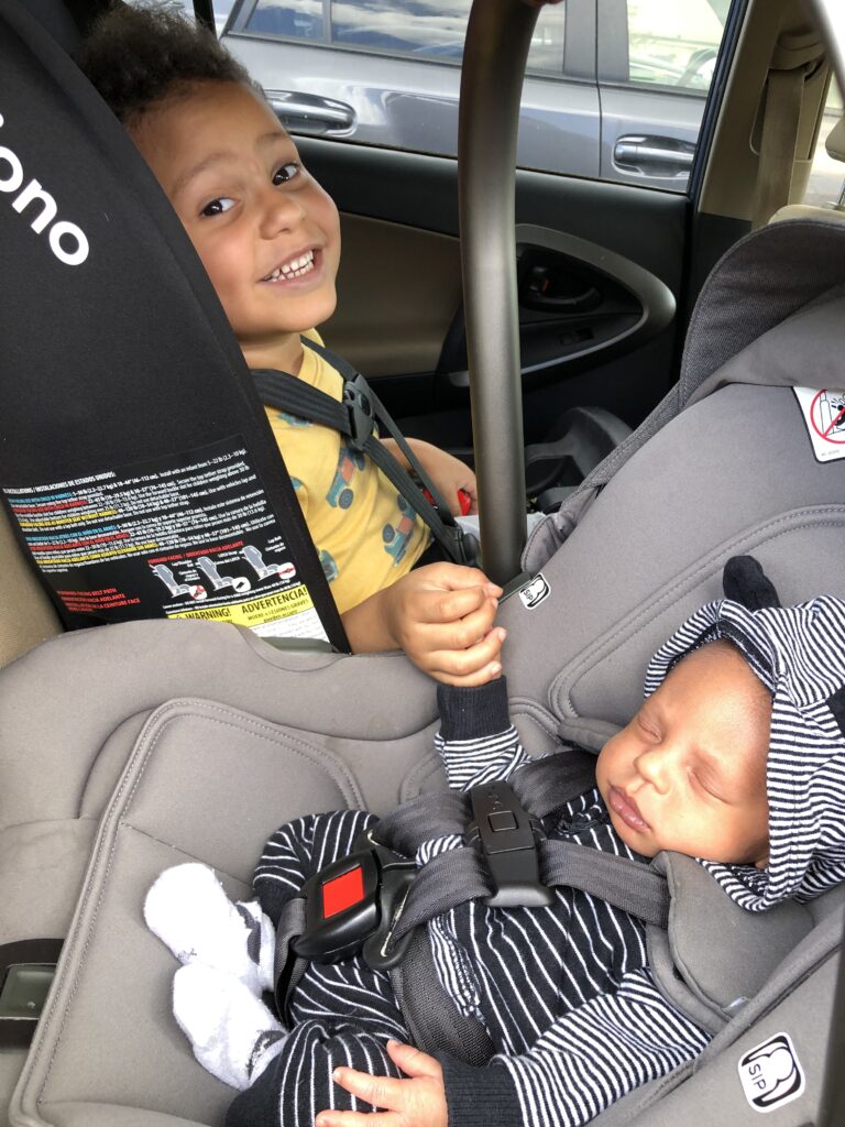 Rear-facing infant and forward-facing toddler after a car seat inspection in Atlanta, showing proper installation for growing families.